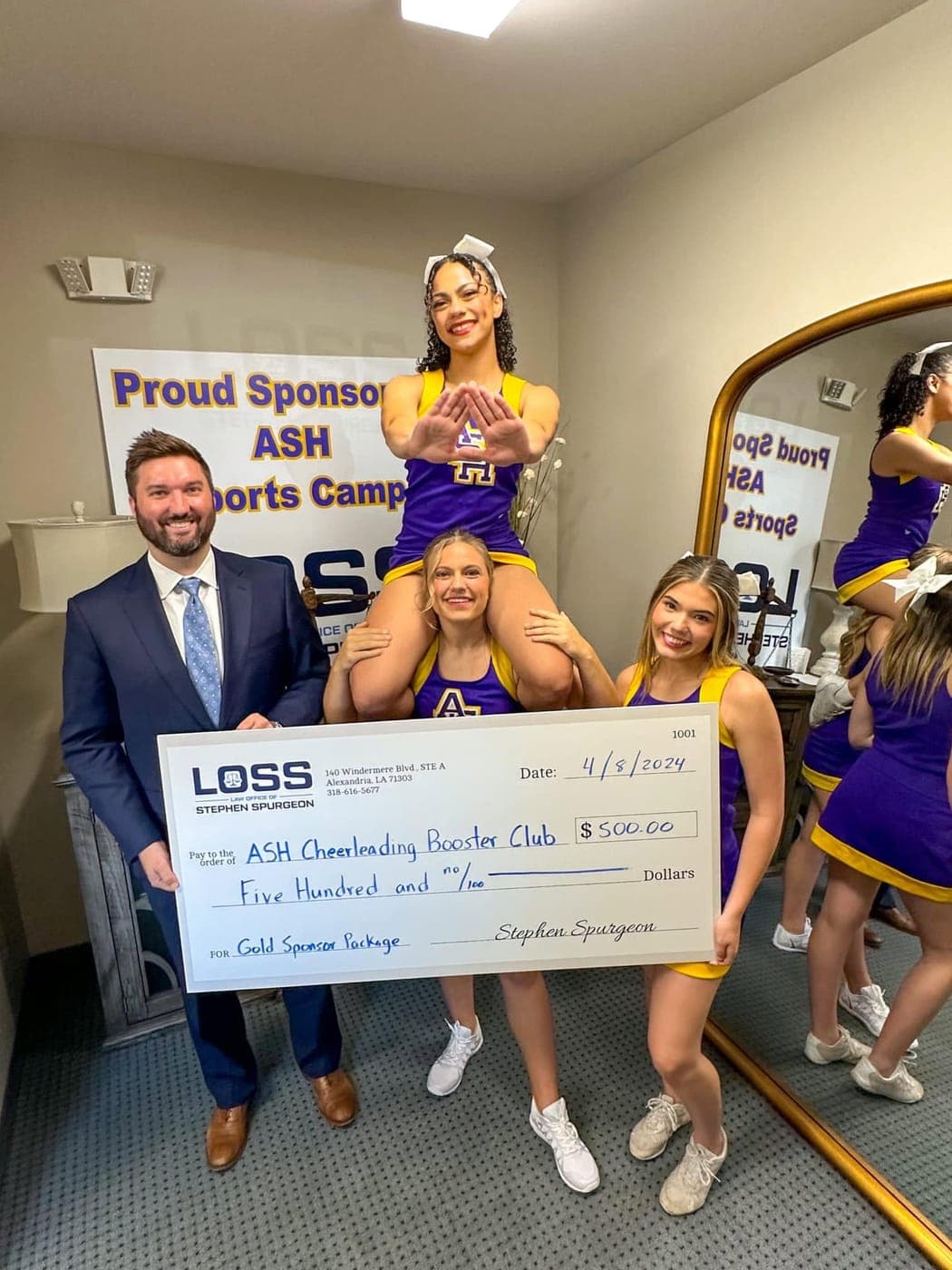 Stephen Spurgeon with ASH cheerleaders holding the firm's sponsorship check for the ASH Cheerleading Booster Club